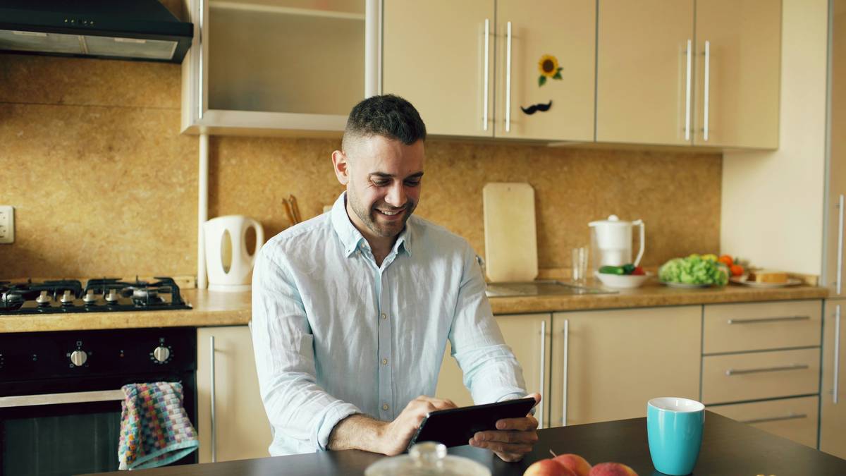 what is a smart dishwasher: close-up of a modern stainless steel smart dishwasher with illuminated display and mobile app interface on a nearby tablet